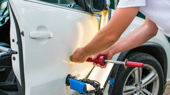 Ein Dellentechniker beim Ausbeulen einer Blechdelle