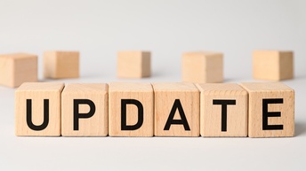 Nebeneinander gereihte Holzwürfel auf einer hellen Oberfläche, die gemeinsam Schriftzug Update ergeben