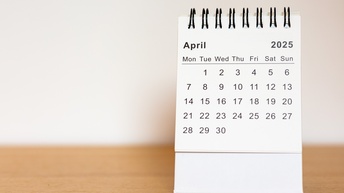 Ein Stehkalender mit dem Monat April und dem Jahr 2025 auf einer Holzoberfläche