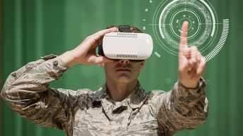 Eine Person in einer Militäruniform trägt eine VR-Brille auf dem Kopf und berührt mit dem linken Zeigefinger eine virtuelle Zielscheibe