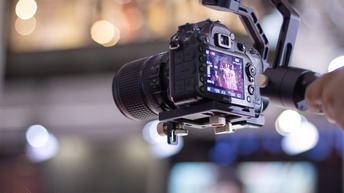 Eine Person nimmt mit einer professionellen, kleinen Kamera ein Video einer Veranstaltung auf