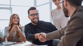Handschlag im Büro mit Businesspartnerinnen und fröhlicher Stimmung
