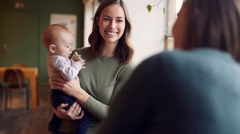Person im Gespräch hält Baby auf dem Arm 
