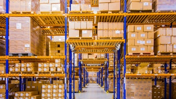 Große Lagerhalle mit gelbblauen Regalen voller Kartonagenboxen