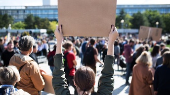 Junge Demonstrations-Teilnehmerin hält ein Schild hoch