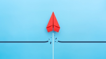 Roter Papierflieger durchbricht eine Linie und startet senkrecht nach oben