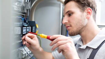 Ein Elektriker schraubt an einem elektrischen Schaltschrank