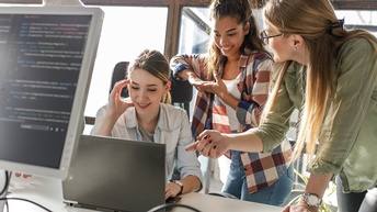 Kolleg:innen im Gespräch vor Laptop-Bildschirm