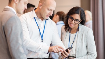 Personen auf einer Konferenz blicken gemeinsam auf ein Smartphone