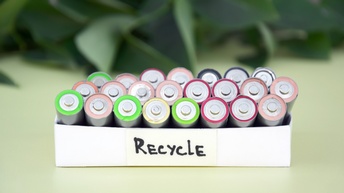 Weiße Schachtel mit der Aufschrift Recycle gefüllt mit Batterien