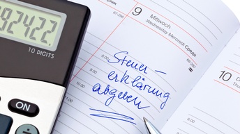 Eintrag in einem physischen Kalenderblatt mit Steuererklärung abgeben, daneben liegt ein Kugelschreiber sowie ein Taschenrechner
