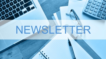 Newsletter Schriftzug vor einem halbtransparentem Hintergrund, dahinter steht ein Laptop auf einem Holzuntergrund sowie liegen Unterlagen, ein Taschenrechner, eine Brille, ein Stift und ein Notizbuch darauf