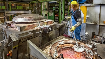Person in Schutzkleidung verarbeitet Aluminium in einer Werkstatt