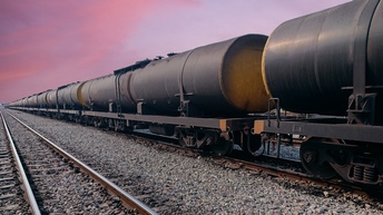 Güterwaggons mit Öltanks auf Schienen bei Sonnenaufgang