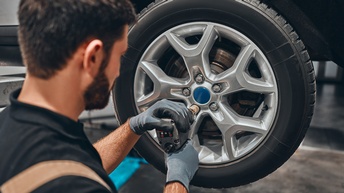 Detailansicht einer Person, die an Autoreifen schraubt