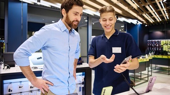 Ein Verkäufer berät einen Kunden beim Kauf eines Smartphones