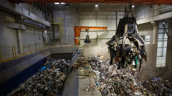 Großer Greifarm voller Müll schwebt über Müllberg in Halle