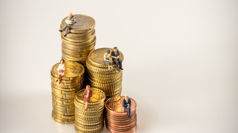 Fünf Türmchen aus aufeinandergestapelten Euro-Münzen, auf denen kleine Figuren von Personen sitzen