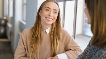 Lächelnde Person im Gespräch mit anderer Person im Ausschnitt