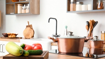 Küche mit glänzendem Kupfer-Kochtopf und frischem Gemüse auf einem Brett