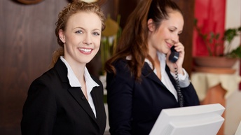 Freundlich lächelnde Empfangsdame an der Hotelrezeption 