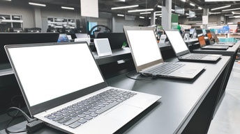 Regal in Elektrofachhandel, auf dem aufgeklappte Laptops nebeneinander stehen