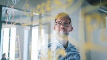 Person mit Brillen blickt auf transparentes, bemaltes Board, der Schriftzug Success erkennbar