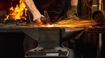 Ein Schmied beim Beschlagen von glühenden Metall