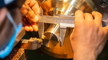 Metalltechniker beim Messen eines Stahlbolzens