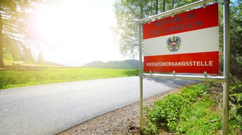 Neben einer asphaltieren Straße steht ein rot-weiß-rotes Schild, auf dem Republik Österreich und Grenzübergangsstelle steht