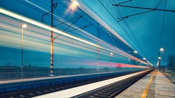 Bahngleis und Bahnsteig im Dämmerlicht im Fokus, ringsum bewegungsunscharfe Lichtlinien