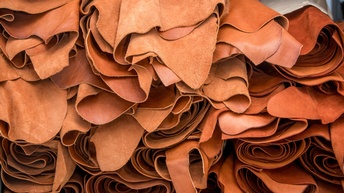 Nahaufnahme vieler über- und nebeneinander gestapelter brauner Lederrollen.