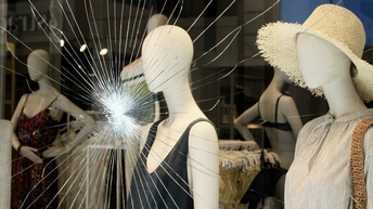 Eine eingeschlagene Fensterfront eines Bekleidungsladens, Vandalismus