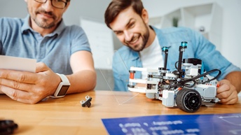 Zwei Personen sitzen bei einem Tisch und arbeiten mit einem Robotor-Prototypen