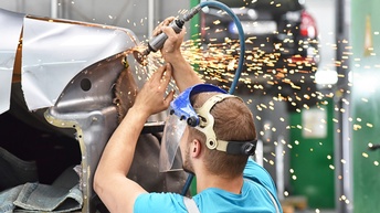 Mechaniker repariert Unfallschaden am Auto in einer Werkstatt