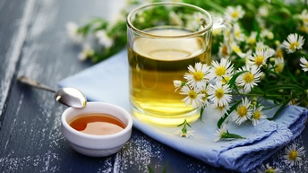 Ein Teeglas mit Kamilletee und Kamillenblühten