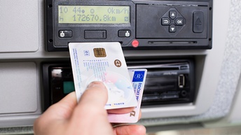 Fahrtenschreiber und Hand, die eine Fahrerkarte und einen Führerschein gemeinsam hält