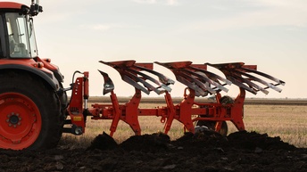 Traktor mit einer Egge beim pflügen eines Feldes
