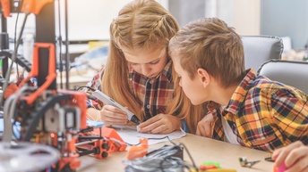 Zwei Kinder arbeiten interessiert mit einem 3D-Stift an einem Schreibtisch