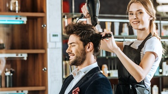 Person wird im Friseurstudio von Friseurin geföhnt