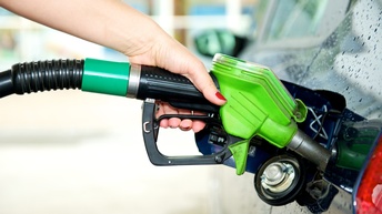 Hand hält Tankstutzen in die Öffnung eines Autotanks