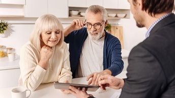 Drei Personen in Küche blicken auf Tablet