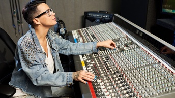 Person mit Brille bedient Mischpult