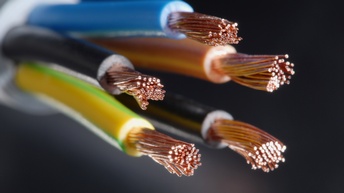 Fünf angeschnittene elektrische Leitungen vor einem dunklen Hintergrund. An den Enden ist die jeweilige Isolierung entfernt, sodass zahlreiche feine Kupferdrähte freiliegen