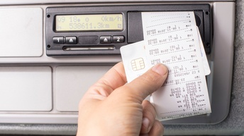 Digitaler Fahrtenschreiber und eine Hand, die einen Ausdruck mit einer Fahrerkarte hält