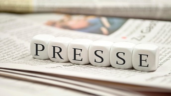 Nebeneinander gereihte Würfel mit dem Schriftzug Presse auf Zeitung liegend