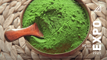 Grünes Matcha Pulver in einer Holzschüssel mit Holzlöffel auf einer geflochtenen Bambusunterlage