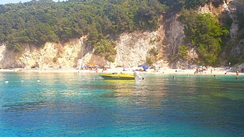 Ein Motorboot im türkisen Wasser vor einer mit Bäumen überwachsenen Steilküste