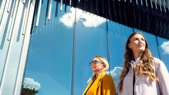 Zwei Frauen vor spiegelnder Fensterfront