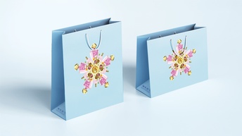 Zwei hellblaue Tragtaschen mit einem aufgedruckten Bild von Parfumflaschen, die einen Stern bilden